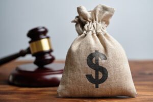 A dollar bag and Judge's gavel in background