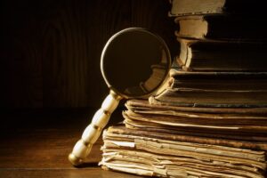 Magnifying glass with ancient books on wooden table.