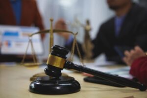 Gavel and scales of justice on a desk with people in the background.