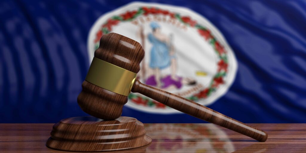 Judge’s gavel on a desk with the Virginia state flag in the background symbolizing law and justice.