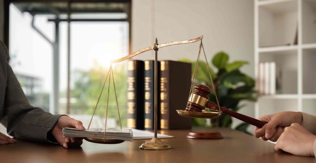 Scales of justice with money and gavel symbolizing legal judgment, settlement, and compensation.
