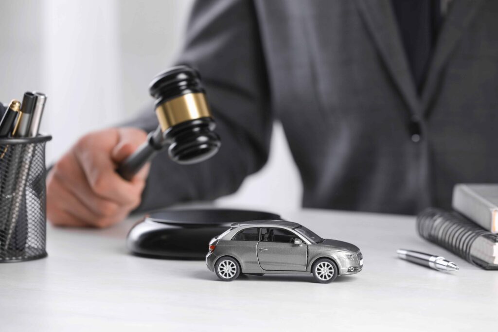 Judge holding gavel near toy car symbolizing car accident lawsuit and auto insurance legal case.