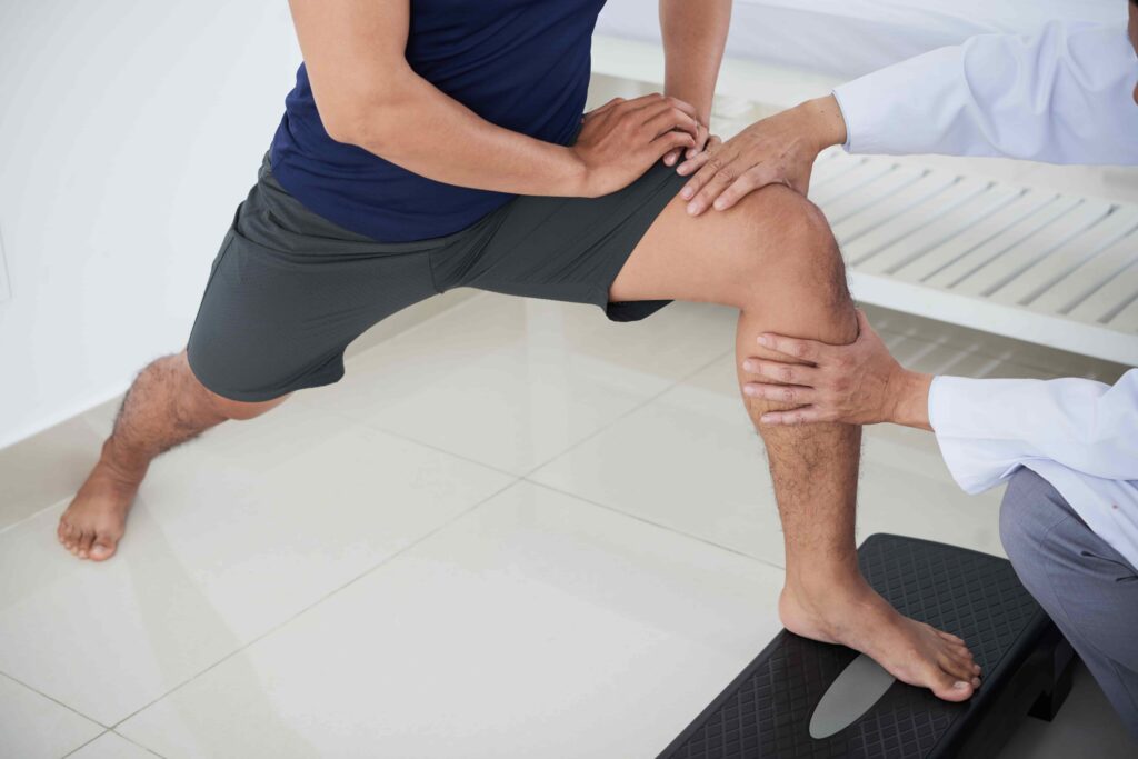 Un fisioterapeuta examina la rodilla de un paciente durante una sesión de rehabilitación, lo que representa el tratamiento de una lesión de rodilla y la recuperación de una lesión personal.
