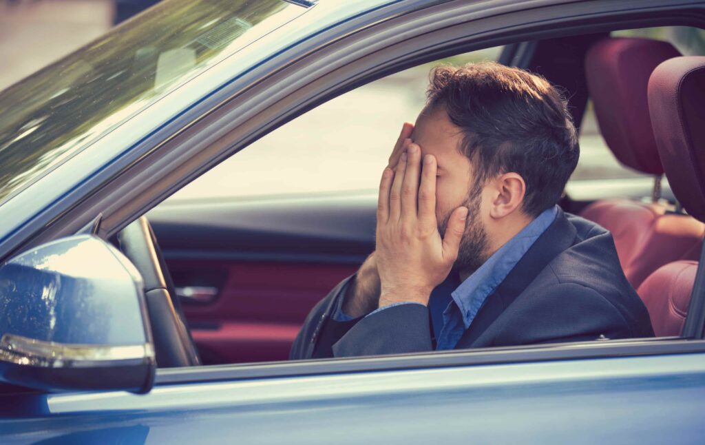 Stressed driver sitting in car with hands covering face after a car accident, illustrating emotional distress following a traffic collision. Stressed driver sitting in car with hands covering face after a car accident, illustrating emotional distress following a traffic collision.