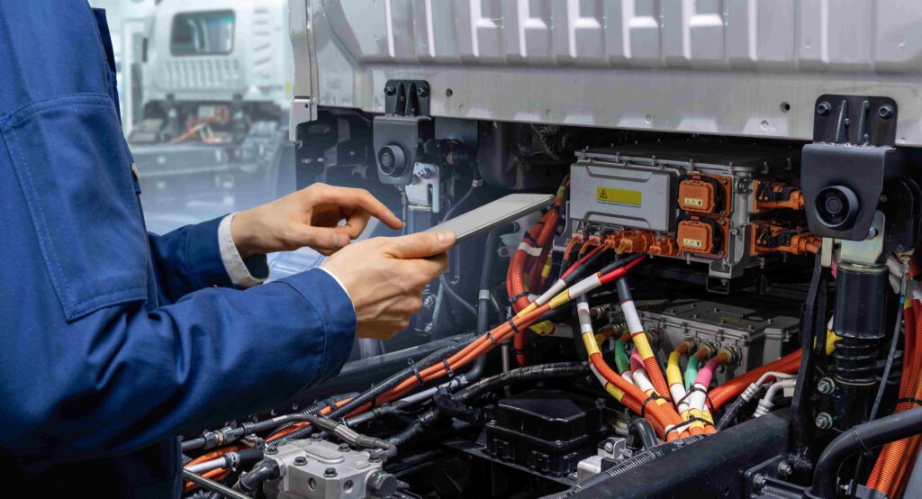 Un técnico inspecciona el sistema de baterías de un camión eléctrico con una tableta, mostrando el mantenimiento de los componentes de alto voltaje en un vehículo eléctrico comercial. Un técnico inspecciona el sistema de baterías de un camión eléctrico con una tableta, mostrando el mantenimiento de los componentes de alto voltaje en un vehículo eléctrico comercial.