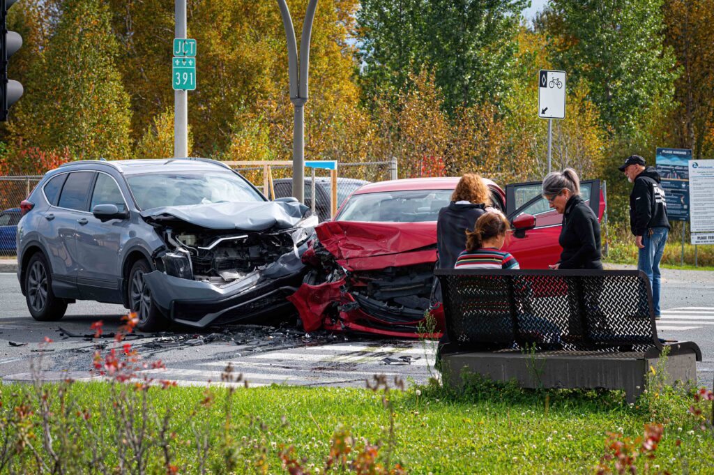 Two vehicles involved in a serious car accident at an intersection with visible front-end damage and bystanders nearby, representing auto collision and personal injury claim scenario.
