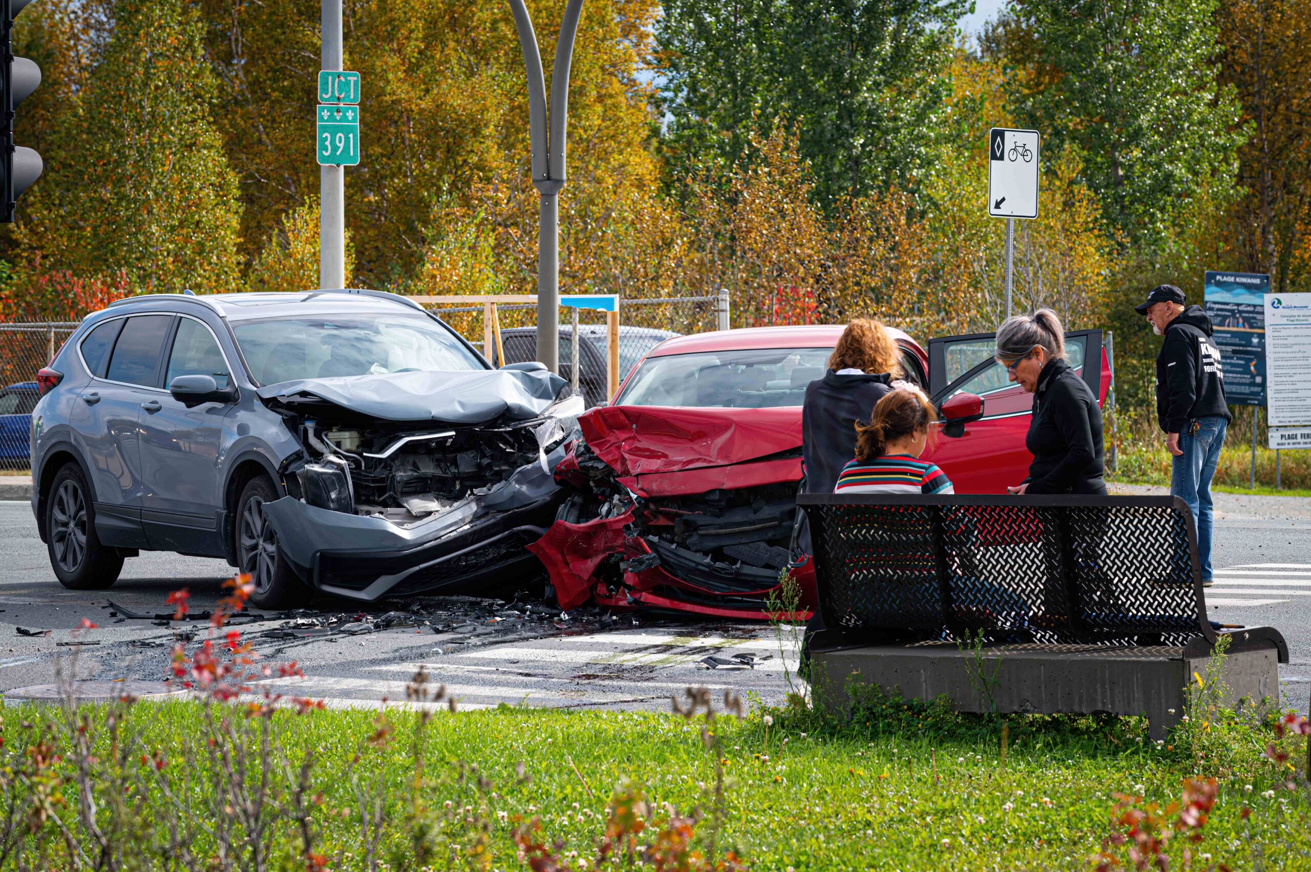 Dos vehículos involucrados en un grave accidente automovilístico en una intersección, con daños visibles en la parte delantera y transeúntes cerca, lo que representa un escenario de colisión automovilística y reclamación por lesiones personales.