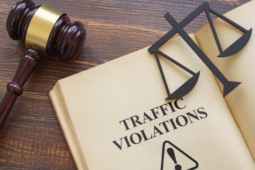 Law book labeled “Traffic Violations” with scales of justice and gavel on desk, representing legal penalties, traffic offenses, and defense services.