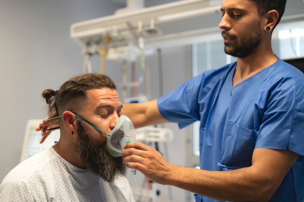 Enfermera realiza evaluación respiratoria a un hombre herido.